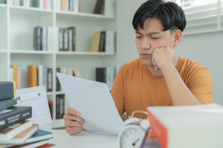 Unhappy Asian man reading document
