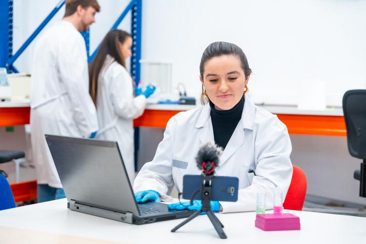 A young scientist uses a laptop and mobile phone in the lab