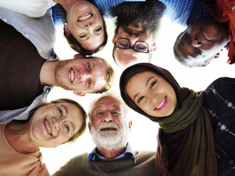 Group of people of various ages and nationalities lean in together