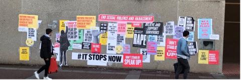 Man walks past wall with anti-harassment posters