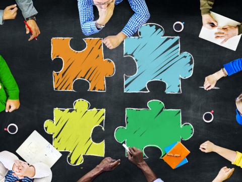illustration-photo composite of people seated around jigsaw pieces