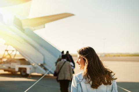 A young woman boards a plane in glorious sunshine