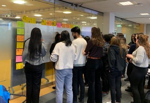 Students standing in front of a whiteboard, ‘joining’ and connecting with each other on the low-tech social network 