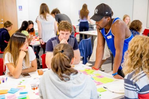 students sitting around a table looking across Post-its for patterns after a storytelling design thinking activity during a Warwick Secret Challenge 