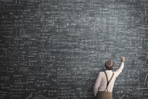 A professor doing sums on a blackboard