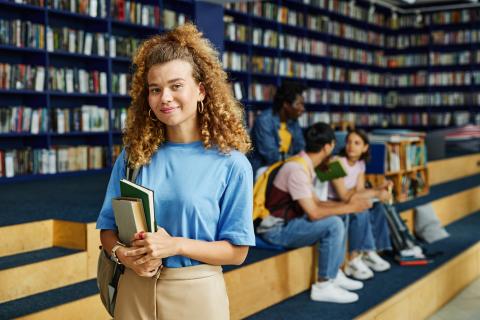 Female student smiling at the camera in a library