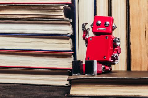 A red toy robot sits on a pile of books