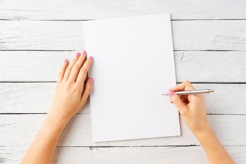 Female hands with a pen and a blank page