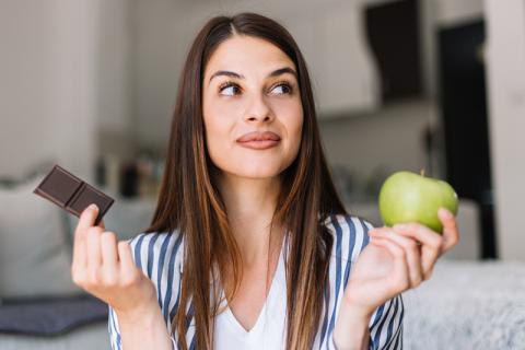 Woman choosing between chocolate and apple