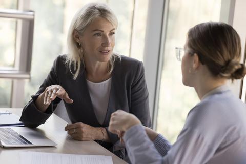 Older woman talking to young woman in a professional setting, mentoring