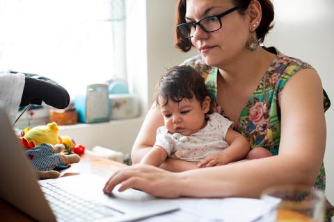 working mother at laptop with toddler