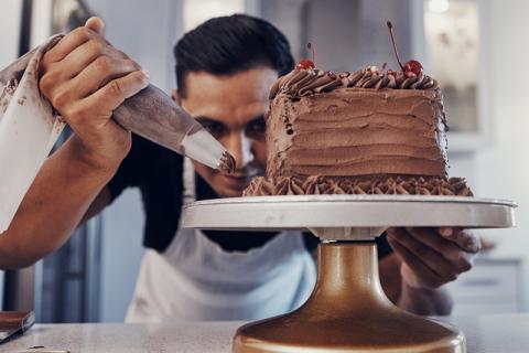 Man putting icing on a chocolate cake