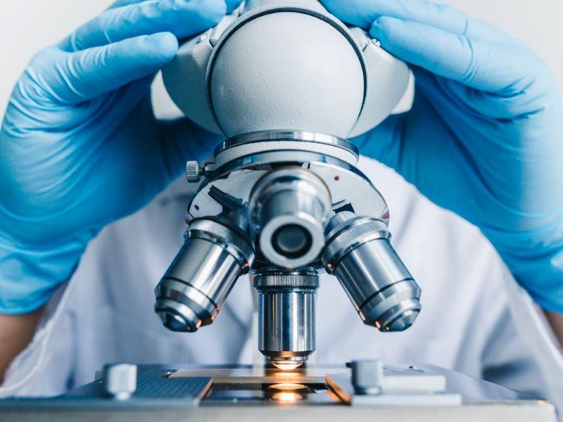 Image of a researcher examining a slide through a microscope