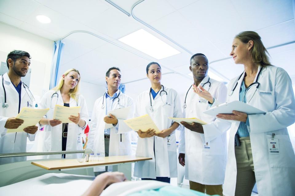 A group of medical students stand around a patient in bed