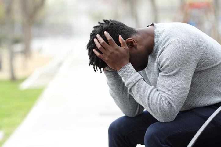 Depressed young black man on a park bench