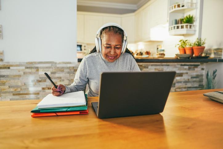 A woman working at her laptop in her kitchen