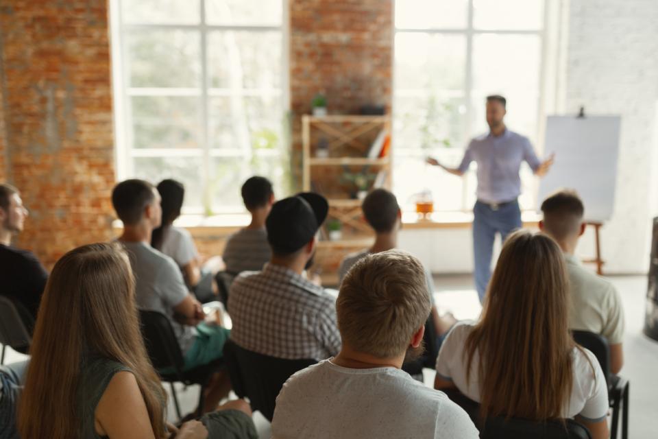 Lecturer standing before a class full of pupils giving a lecture