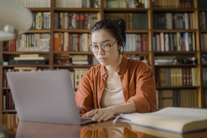 Asian academic at laptop in library