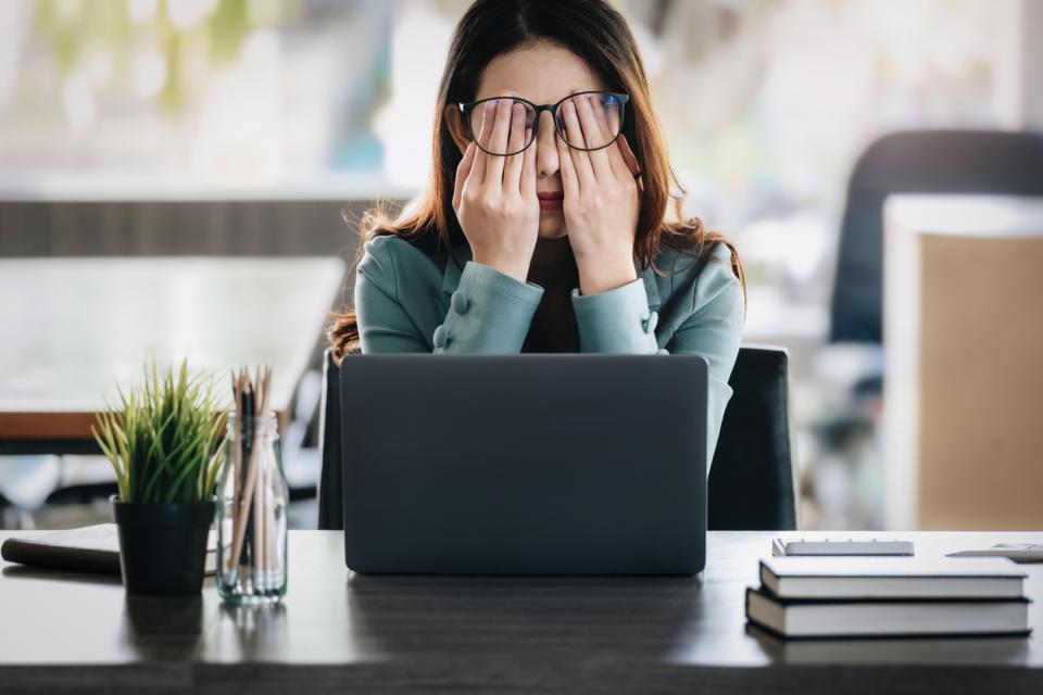 Woman sitting at her laptop with her head in her hands