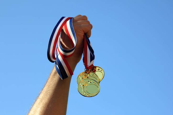 Hand holding three gold medals