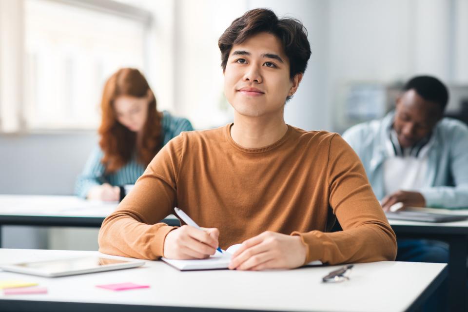 Student sat at a desk listening to an off-screen teacher in cass 