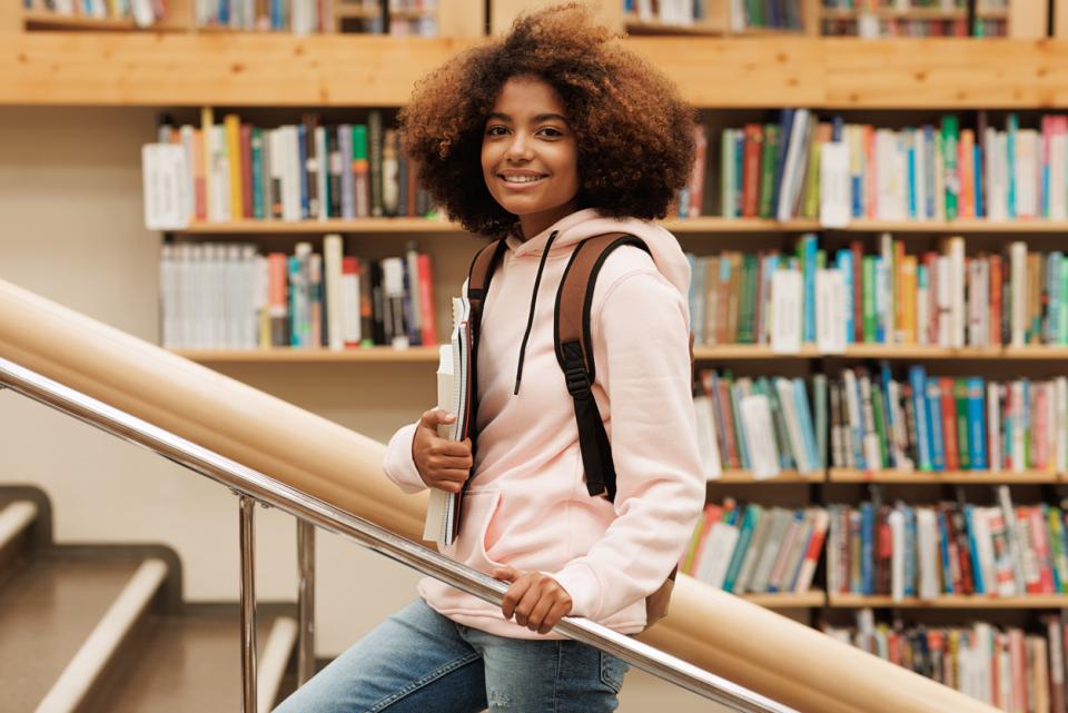 Young student standign on a staircase in a library