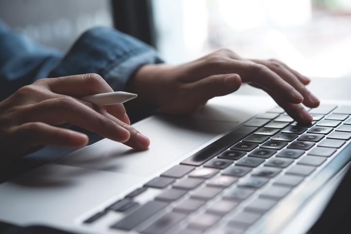 Hands type at a laptop keyboard