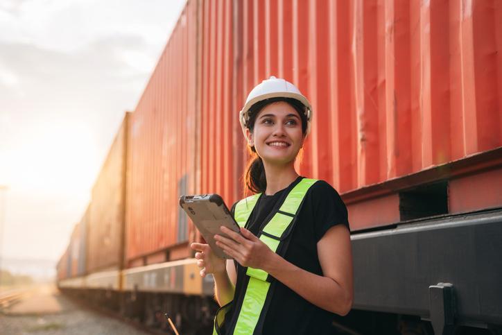 A young woman in a hard hat checks inventory on a tablet