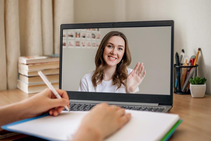 A young woman presents on a screen as someone takes notes