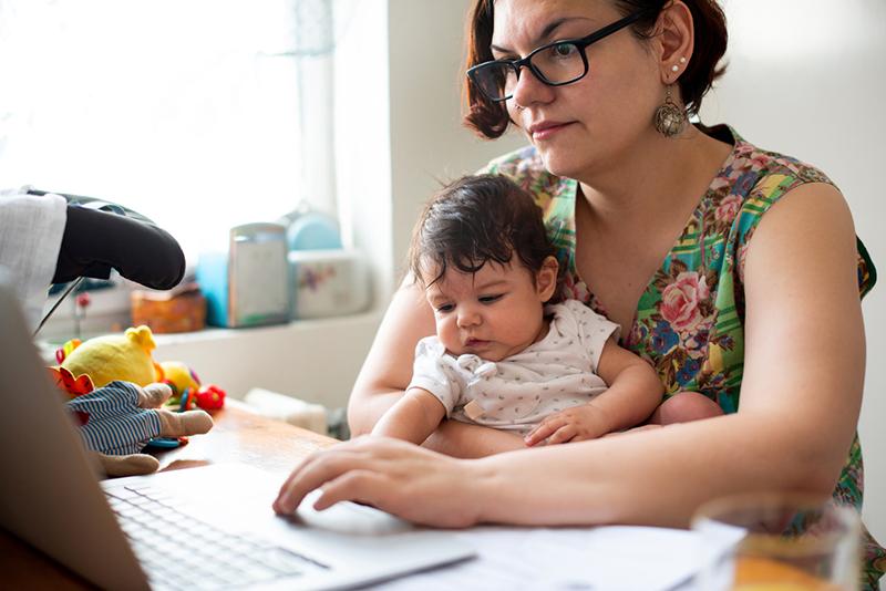 working mother at laptop with toddler