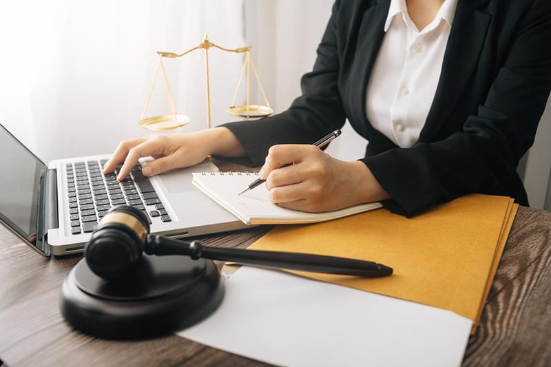 young woman working at laptop with gavel in foreground