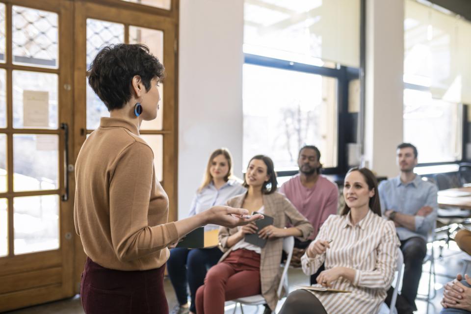 A teacher giving a lecture to a diverse class full of students