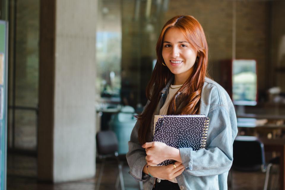 Student holding her books smiling to camera