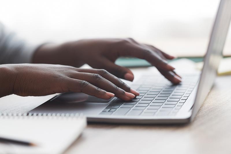 Hands of black woman typing on laptop