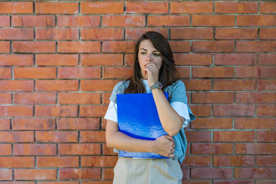 A student standing outside campus thinking