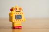 A yellow toy robot waves hello