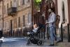 Student father pushing a pram across the street