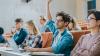 A student raises his hand in a lecture hall